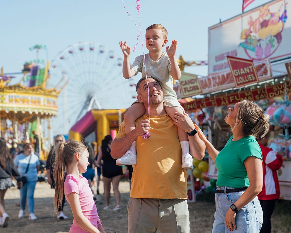 A child on a parent's shoulders at a county fair midway